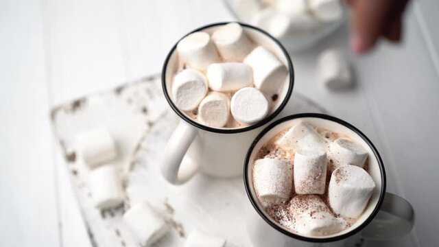 Sprinkling chocolate on marshmallows in mug with cocoa, top view