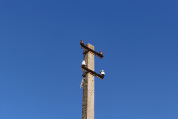 One old electric pole without wires against a blue sky.