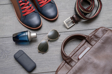 Top view of men set shoes, belt, bag, perfume on wooden background