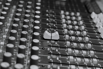 Analog mixing console close up. Black and white photo.