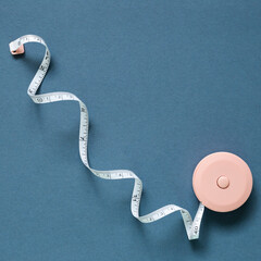 Pink tape measure on navy blue background. top view, copy space