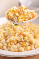 Eating Chinese fried rice in white plate on bright wooden table background.