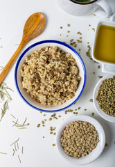 Bulgur pilaf with green lentils with thyme seeds and olive oil on a white background.