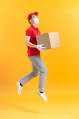 delivery man with face mask and gloves holding a cardboard box and jumping