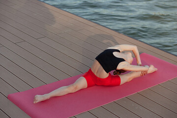 Beautiful young slim girl doing yoga or gymnastic exercise by the lake. Healthy lifestyle....