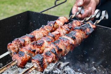 Meat skewers grill. Pork or beef are fried on open fire. Barbecue kitchen party close up image. Kebab or shashlik cooking on spits