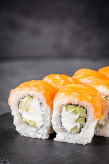 appetizing philadelphia sushi roll with salmon and cucumber on a black stone plate