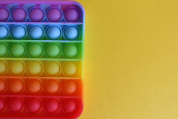 The toy anti-stress popit simple dimple view from above on a yellow background with a place for text and with a copyspace