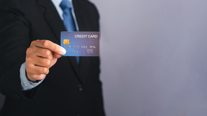 Businessman holding a mockup blue credit card while standing in a studio with copy space for text. Close-up photo. Money and business concept