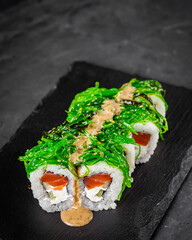appetizing sushi roll with philadelphia cheese cucumber salmon and chuka on a black stone plate