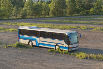 The bus stands in a field on a dirt road