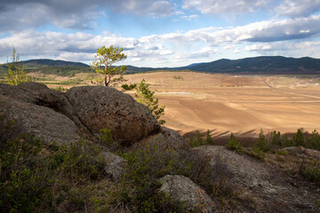 Fototapeta na wymiar plowed field, arable land, among the rocks, blue sky with clouds, landscape