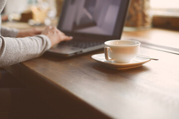 Hands of a woman working on a laptop. A freelance worker completes an order in a cafe.