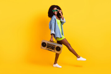 Fototapeta na wymiar Full length body size view of attractive cheerful girl dj deejay carrying tape player isolated over bright yellow color background