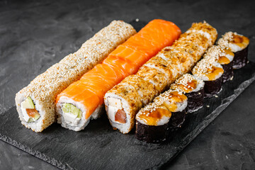 appetizing set of sushi roll on a black stone plate