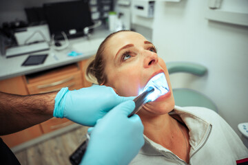 Caucasian female teen sitting in dentist chair having teeth cleaned 