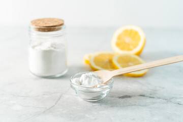 Eco friendly natural cleaners, jar with baking soda, lemon and wooden spoon on marble table...
