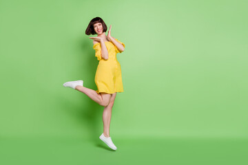 Full length body size view of attractive cheerful lucky girl having fun jumping isolated over green color background