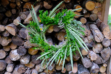 A wreath of flowers, bent and greenery hung at a ridge of firewood during the summer solstice festival