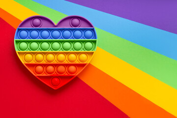 Colorful trendy Pop it fidgets toy on a rainbow background. Toy anti-stress, simple dimple. LGBT concept - obrazy, fototapety, plakaty