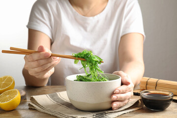 Woman eating Japanese seaweed salad at table, closeup