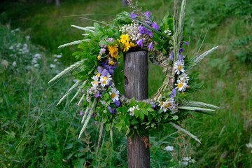 Colorful wreath of flowers, bent and twigs, hung on a wooden pole during the summer solstice festival