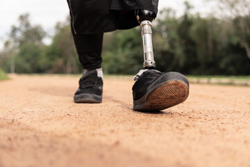 detail of man with prosthetic leg walking in dirt at park..