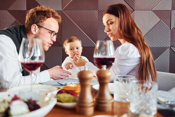 Young guy, woman and little boy. Indoors of new modern luxury restaurant