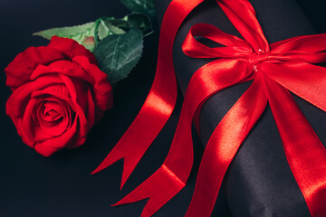 gift with red bow and rose on black background