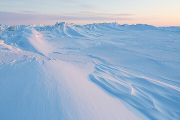 Fototapeta na wymiar Winter arctic landscape. Ice hummocks on the frozen sea in the Arctic. Cold frosty winter weather. Harsh polar climate. View of snow and ice at sunset. Snow-covered expanses of the Arctic. Far North.