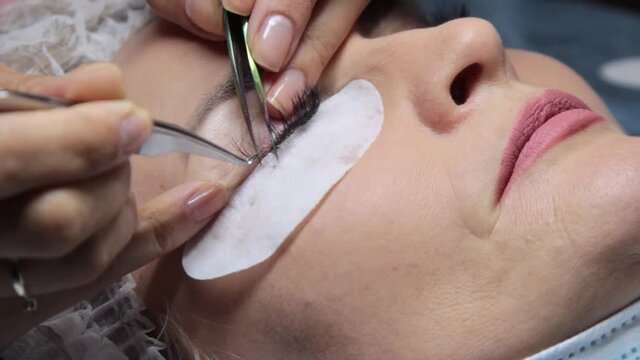 beauty salon. close-up, eyelash extension procedure. The master glues each eyelash with special glue, works with two tweezers