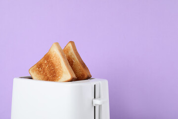 Modern toaster with slices of bread on lilac background, closeup. Space for text