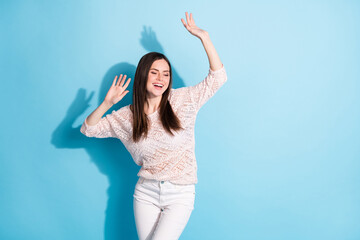 Photo of attractive joyful young woman raise hands dance smile isolated on pastel blue color background