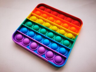 Anti-stress toy poppit. Push bubble toy. Rainbow colors. Close-up. Colored abstract background.