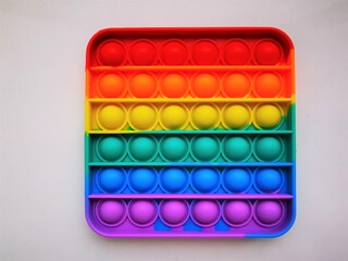 Anti-stress toy poppit. Push bubble toy. Rainbow colors. Close-up. Colored abstract background.