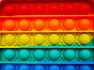 Anti-stress toy poppit. Push bubble toy. Rainbow colors. Close-up. Colored abstract background.
