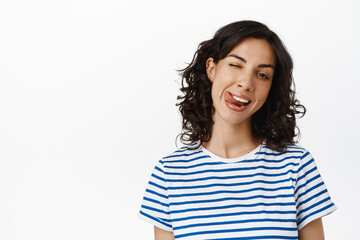 Emotions and people concept. Happy brunette girl showing tongue, winking and smiling happy,...