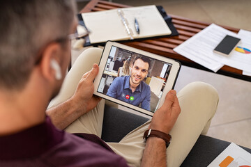Businessman doing video call with colleague from home - obrazy, fototapety, plakaty