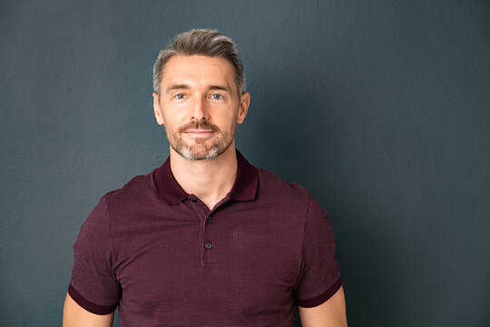 Handsome Mature Man Looking At Camera On Gray Wall