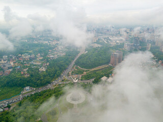Fototapeta premium Motherland monument in Kiev between the clouds. Aerial drone view.