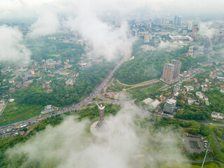 Fototapeta premium Motherland monument in Kiev between the clouds. Aerial drone view.