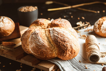 Bread on dark background. Fresh crispy baking, old style. - obrazy, fototapety, plakaty