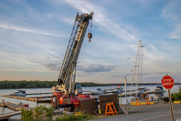 Crane on the dock of a yacht club preparing to lift boats into water near dusk nobody