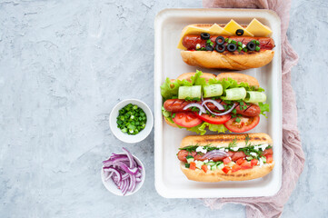 Top view of a delicious freshly cooked hot dogs fully loaded with assorted toppings on a tray.