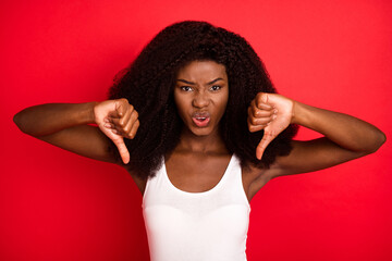 Photo of young african girl unhappy upset negative thumb-down dislike isolated over red color...