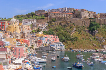 Fototapeta na wymiar Panoramic view of Procida, Italian Capital of Culture 2022: colorful houses, cafes and restaurants, fishing boats and yachts in Marina Corricella , in Gulf of Naples, Campania, Italy.