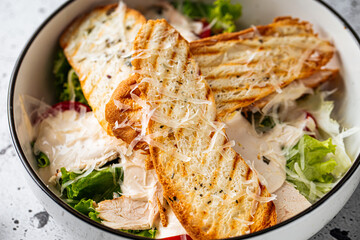 Bowl of fresh chicken caesar salad on light decorated background