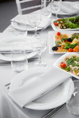 
Beautifully set table in the banquet hall of the restaurant. A table with appetizers for wine, cold dishes and salads. White tablecloths and napkins