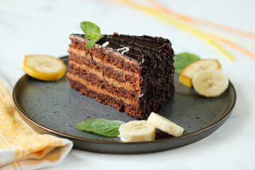 Fresh chocolate cake with banana slices and mint on plate