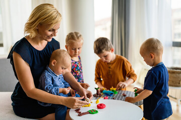 Obraz premium Kids playing with plasticine. Teacher or mother play with children. People, kid creativity concept